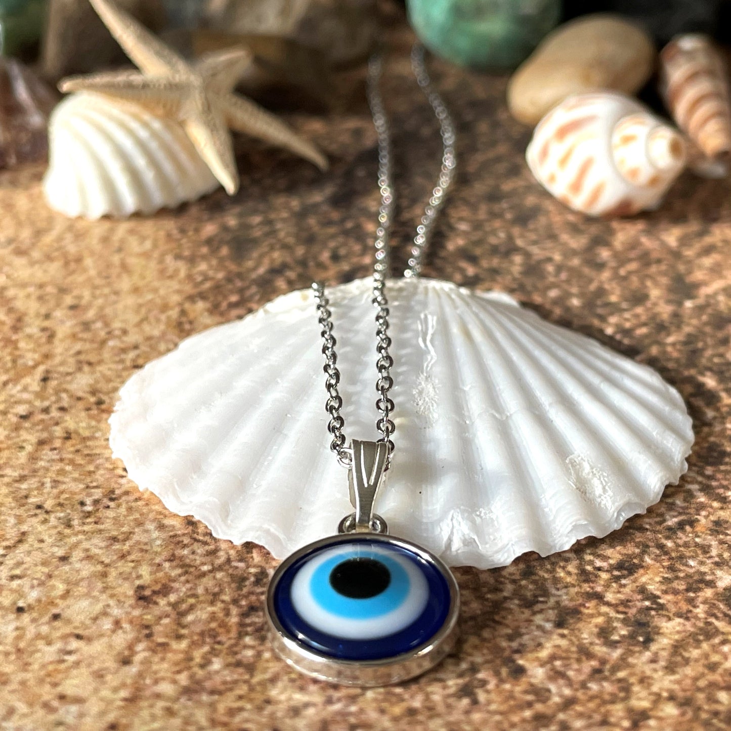Evil eye necklace on a shell with seashells in the background