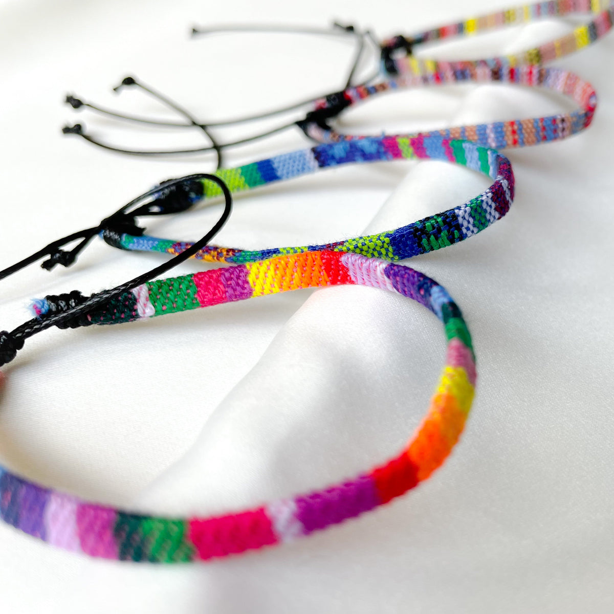 Close-up view of colorful woven anklets on a white background