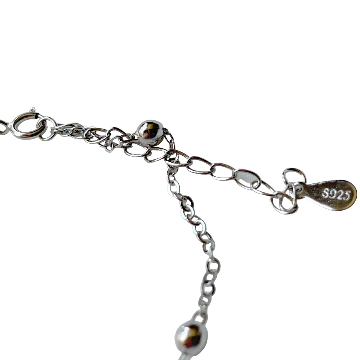 Silver ankle bracelet with chain, beads and S925 hallmark tag on a white background