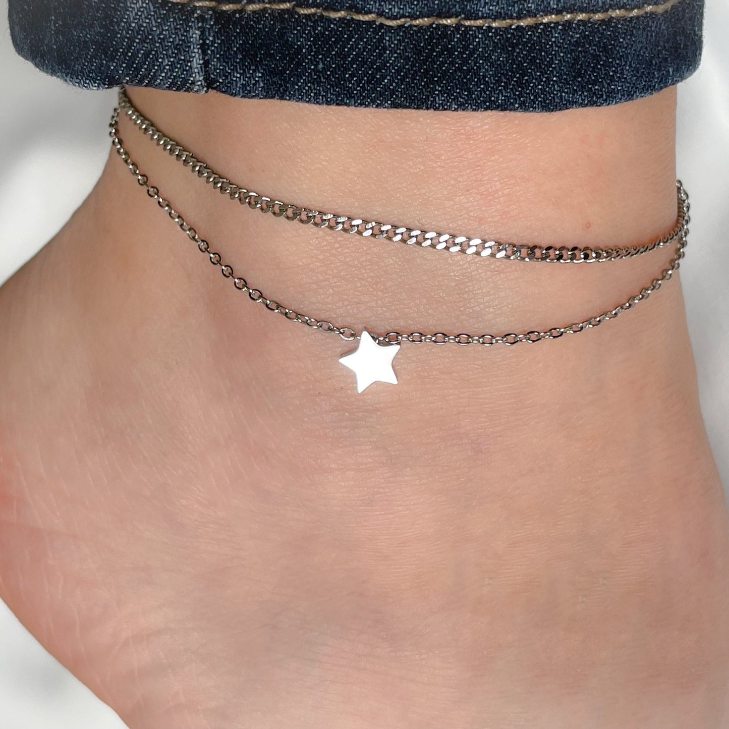 Star-shaped anklet on a person's ankle, with star charm reflecting light against a blurred background