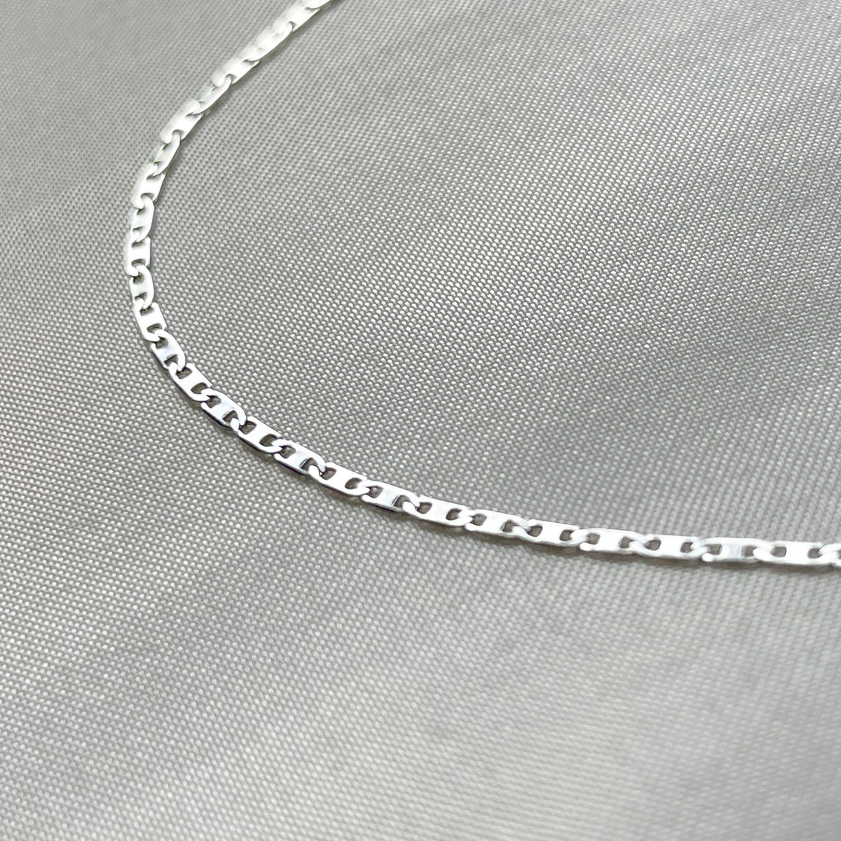 Silver chain necklace on a gray fabric background