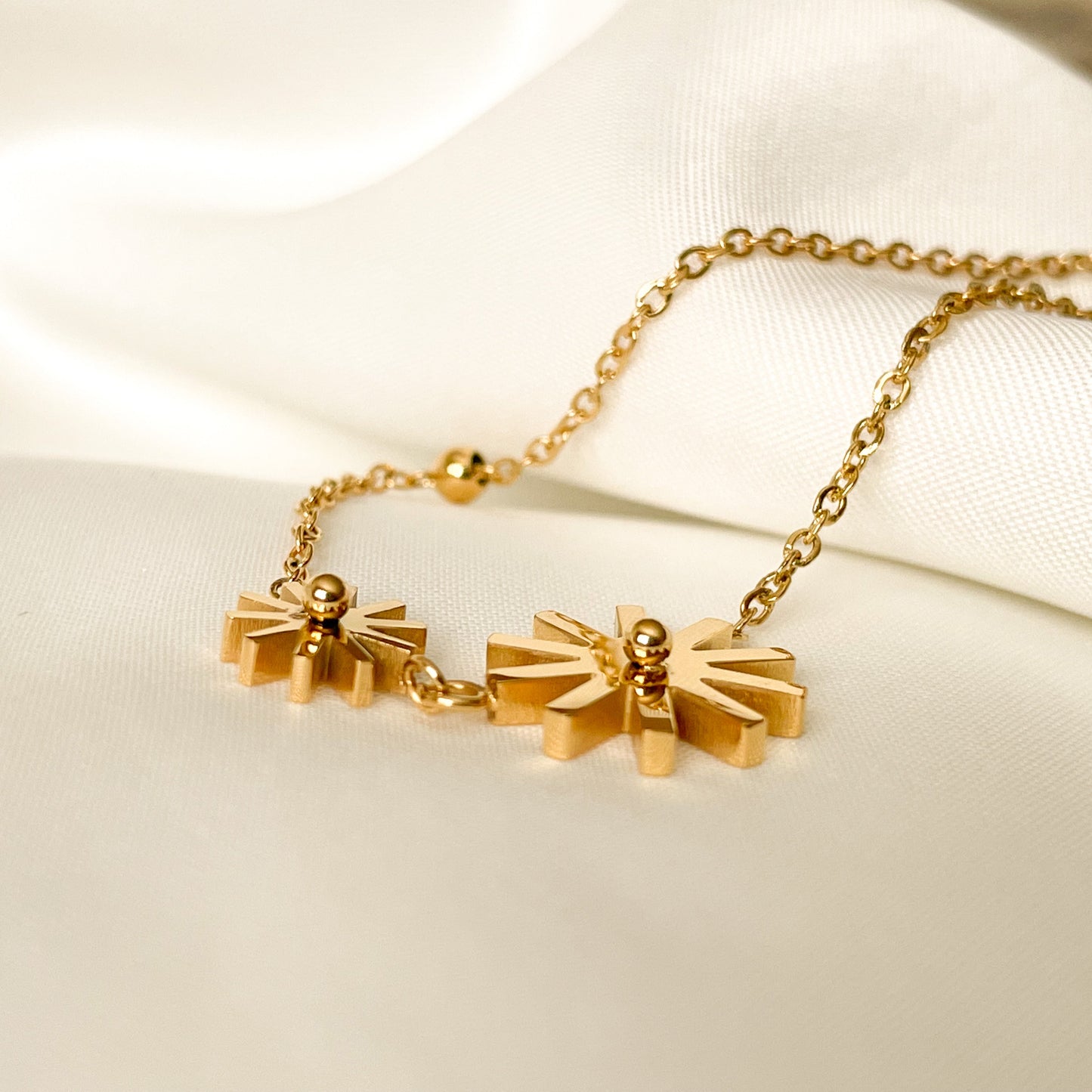 Gold anklet with decorative sunflower pendants on a light background