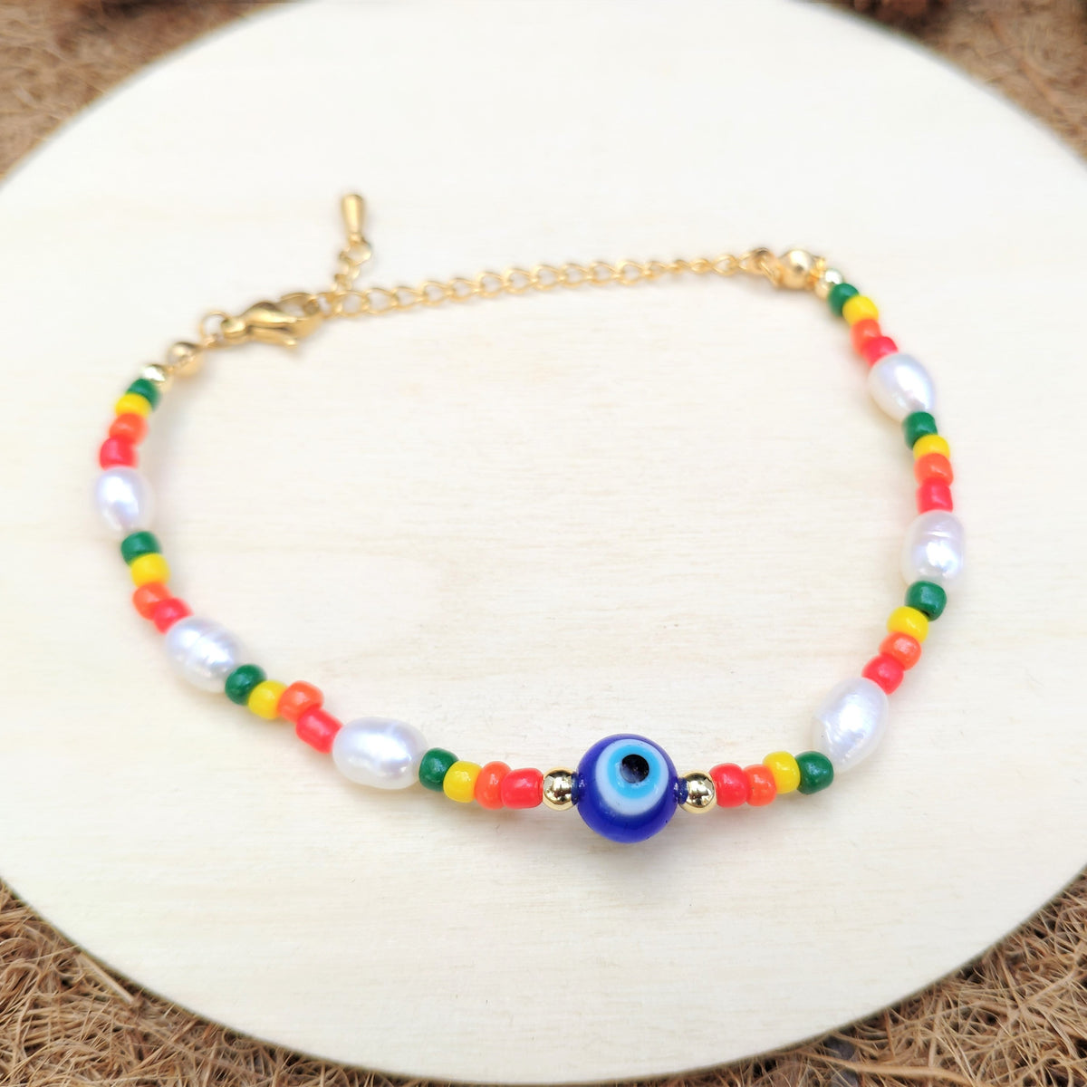 Colorful beaded pearl bracelet with a blue evil eye bead on a white plate.