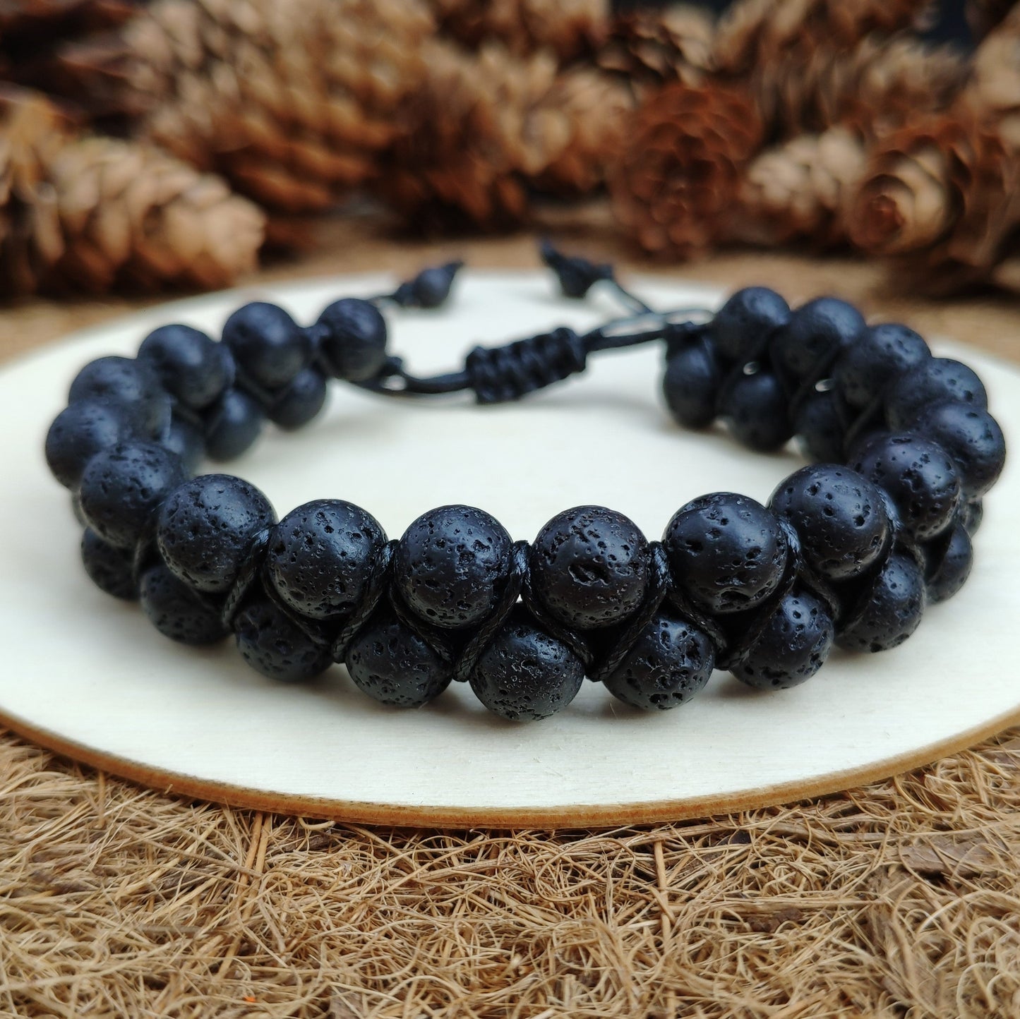 Front view of the black beaded bracelet on a white plate with a textured brown background