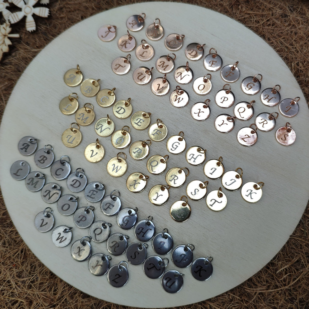 Assorted metal charms with letters and numbers on a round white board.