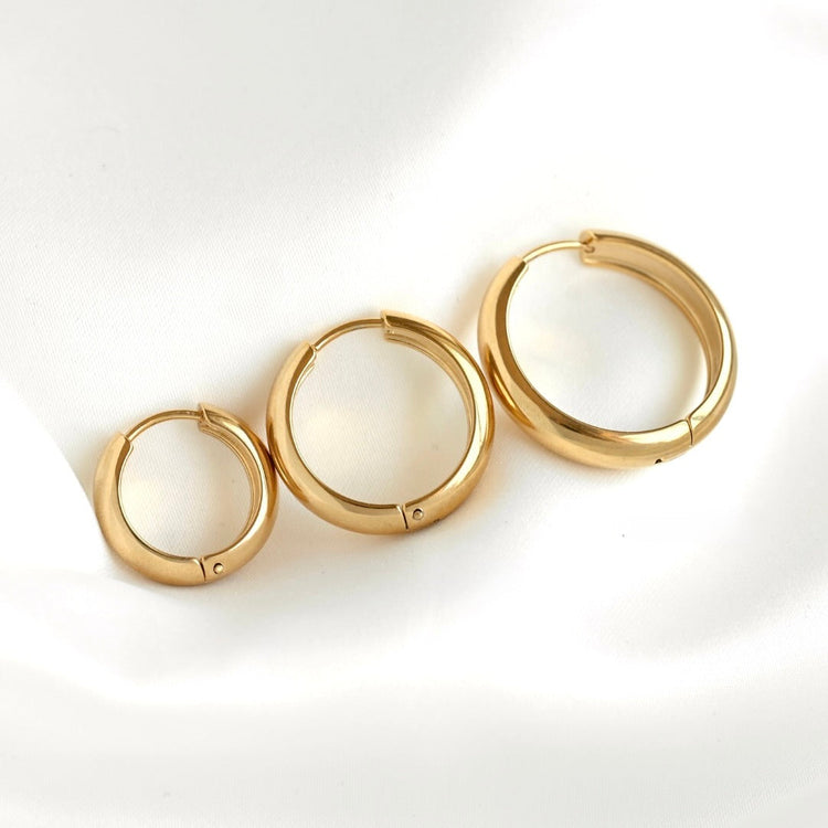 Dazzling stainless steel earrings on white satin: oversized chunky hoops, small diamond accents, and classic thin hoops - perfect for every occasion
