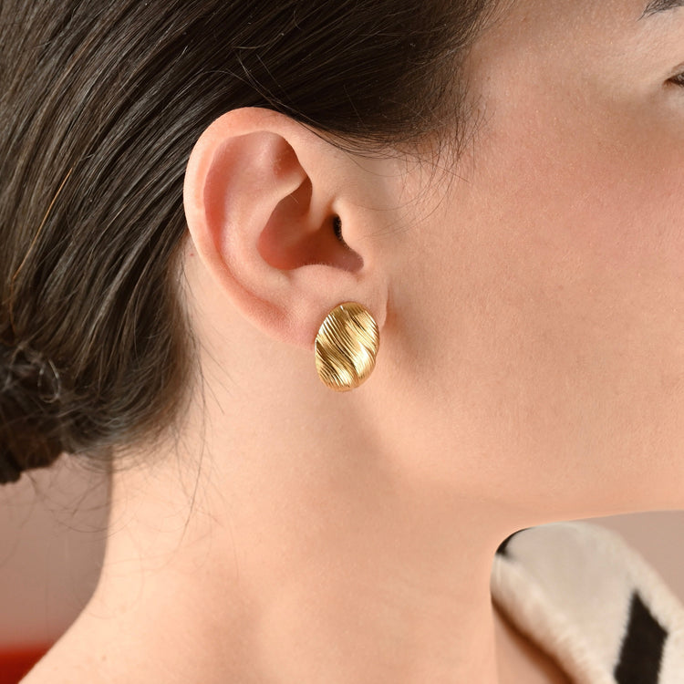 Female model is wearing medium oval diagonally striped drop earrings.