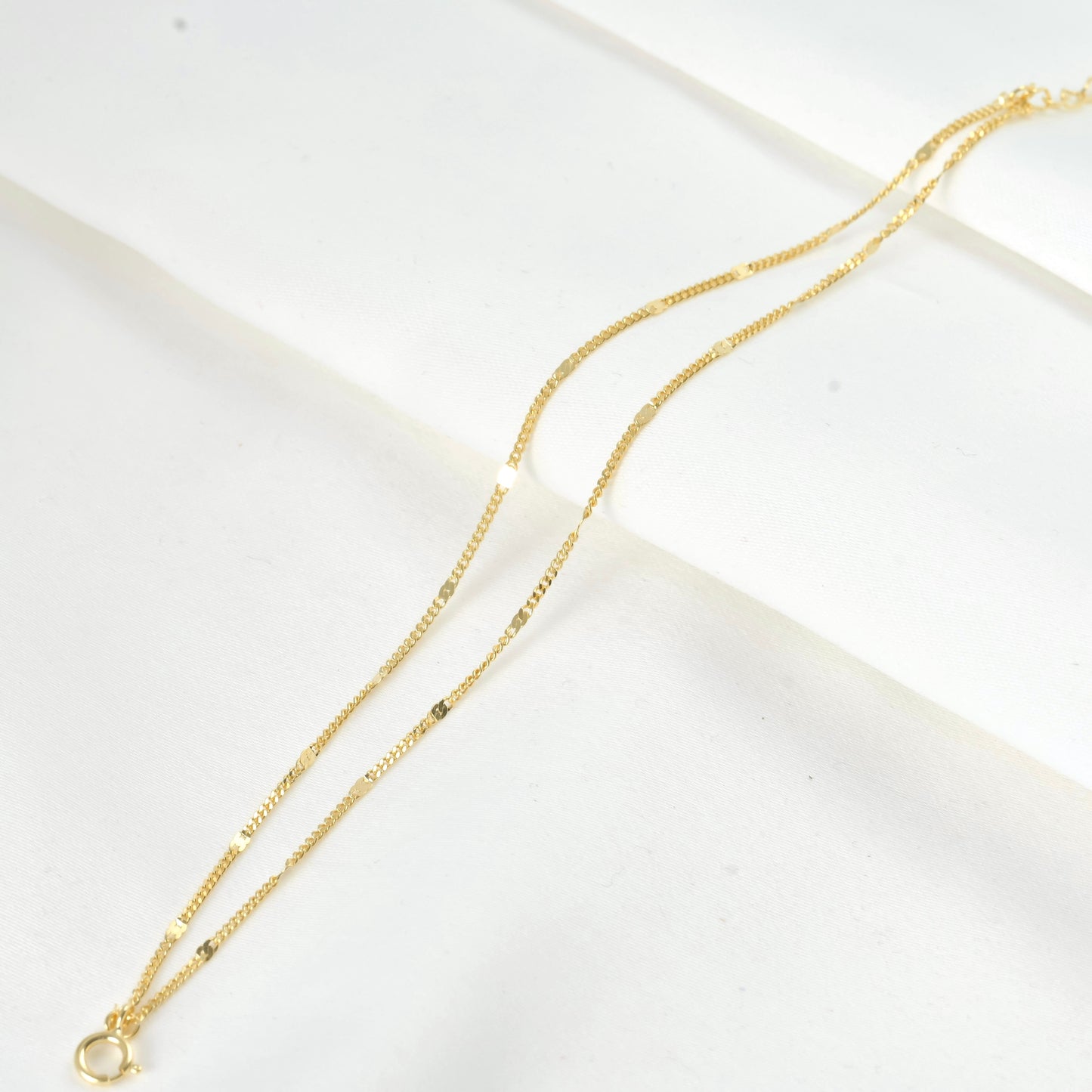 Sleek gold chain bracelet on a white surface
