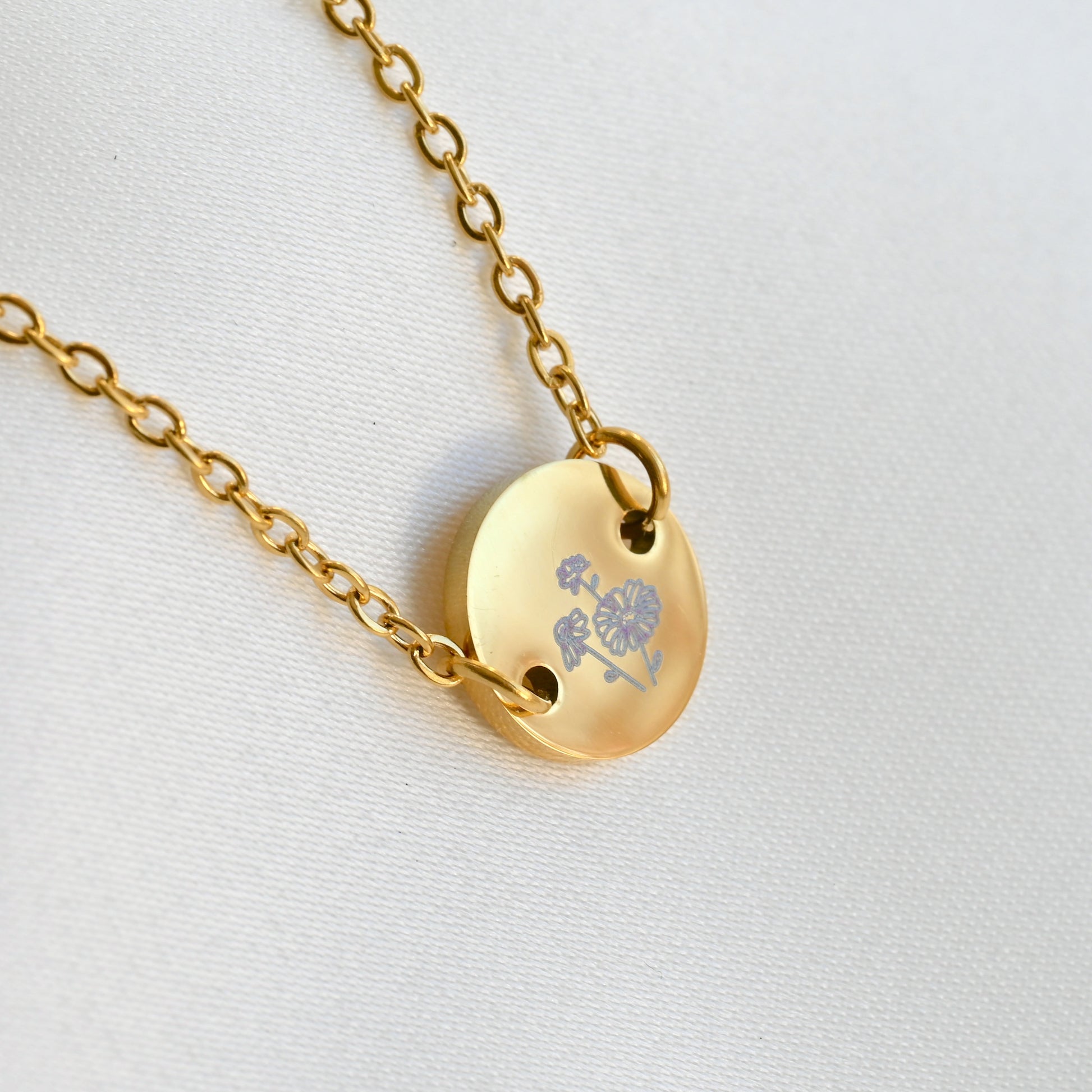 Side close up view of gold april birth flower bracelet on a light gray background