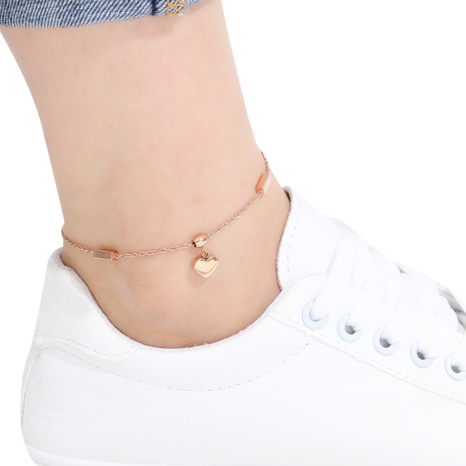 Rose gold anklets on a person's ankle with a white sneaker and light background