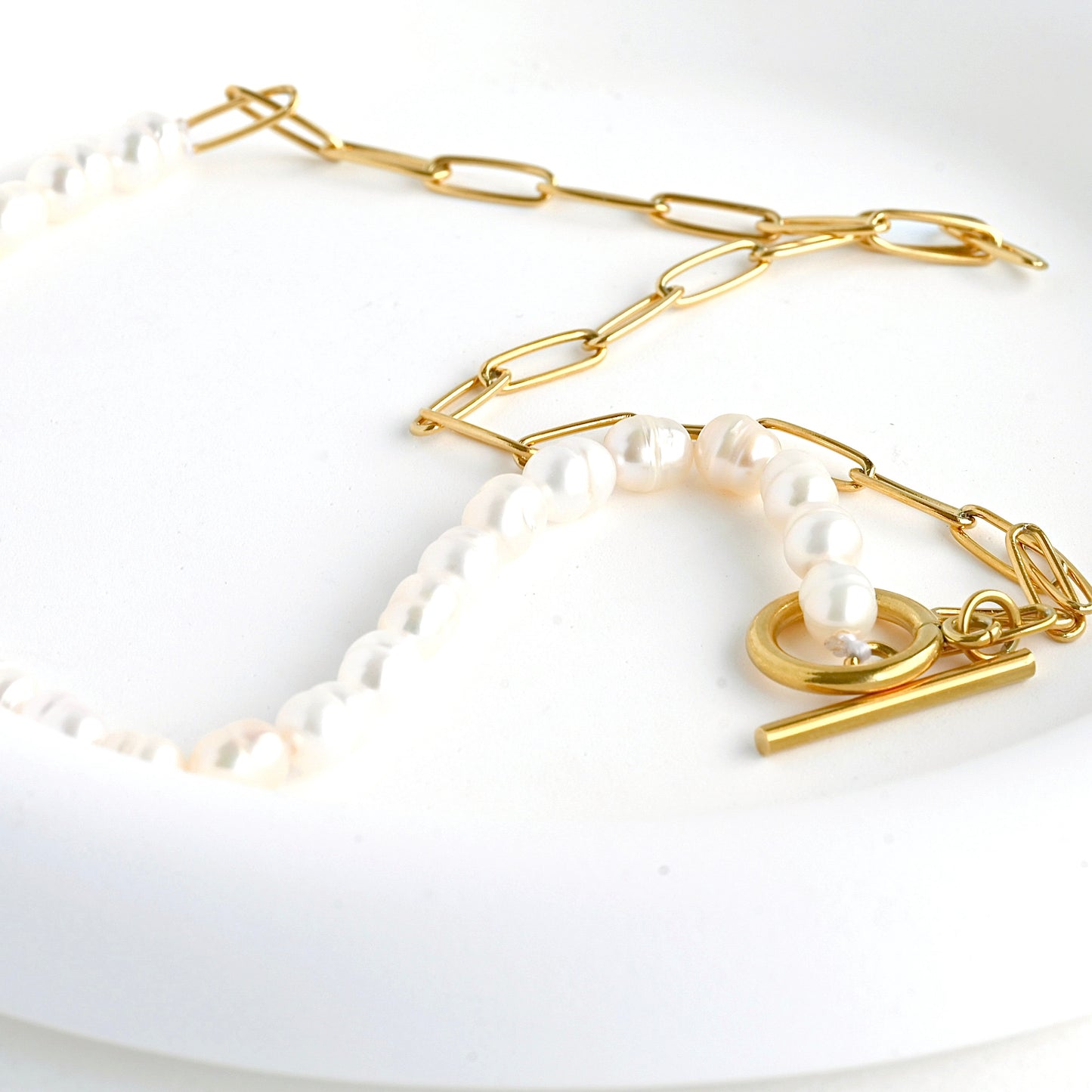 Gold pearl chain necklace from a different angle in a white dish