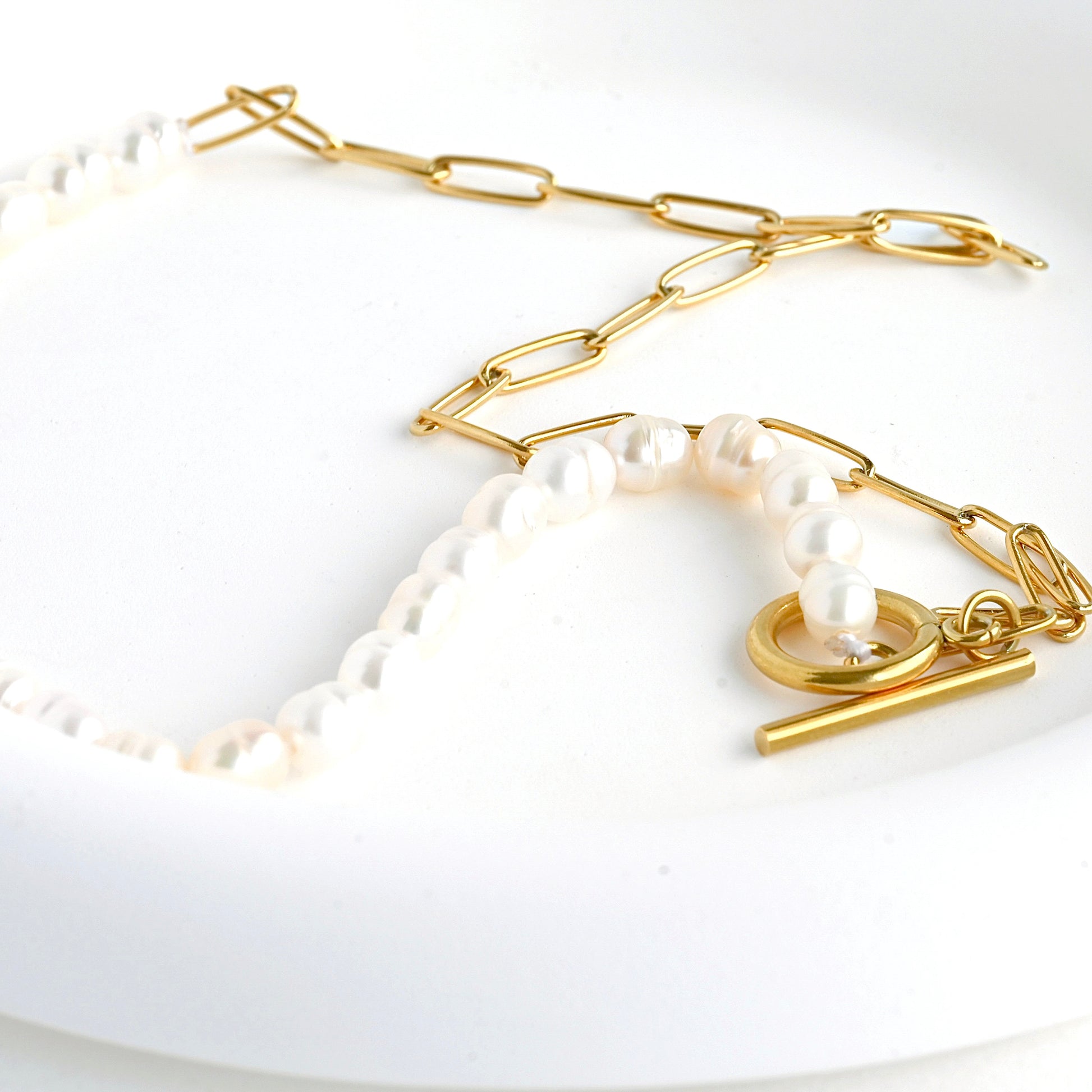 Gold pearl chain necklace from a different angle in a white dish