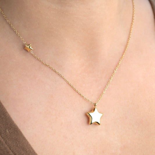 Gold puffed star necklace on a person's neck