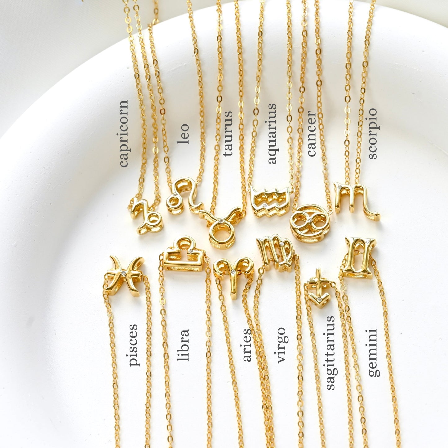 Gold necklaces with zodiac symbols on a white background