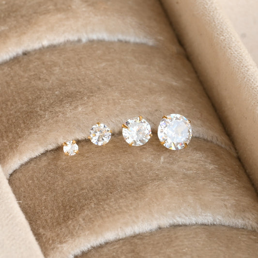 diamond stud earrings in four sizes on a beige fabric background