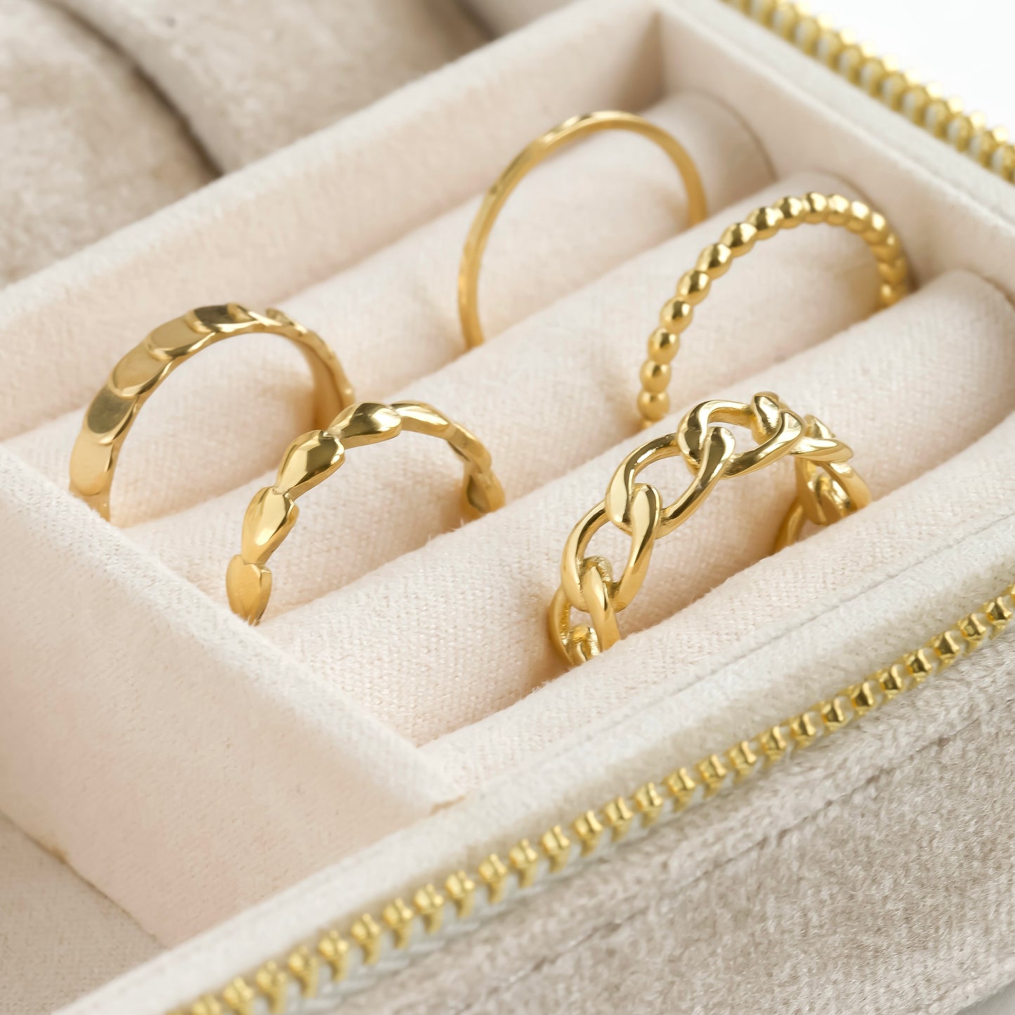 Gold rings displayed in a jewelry box with a beige interior.