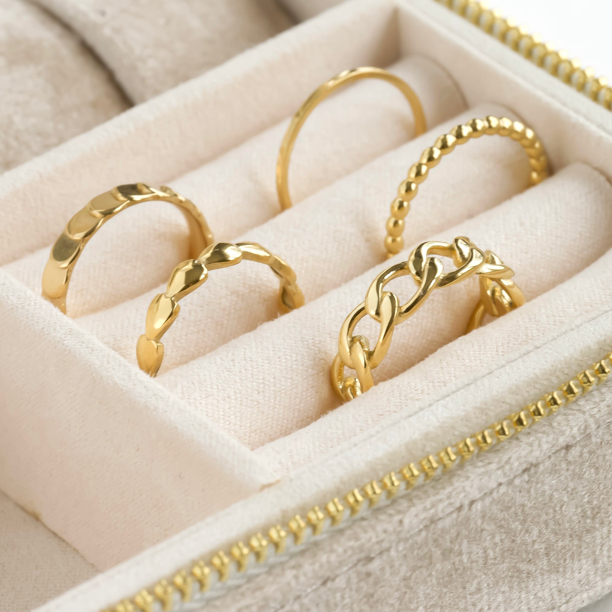 Gold rings displayed in a jewelry box with a beige interior.