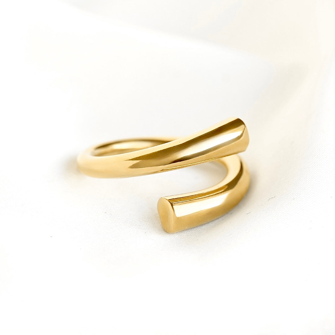 Close up view of a chunky gold open wrap ring on white surface