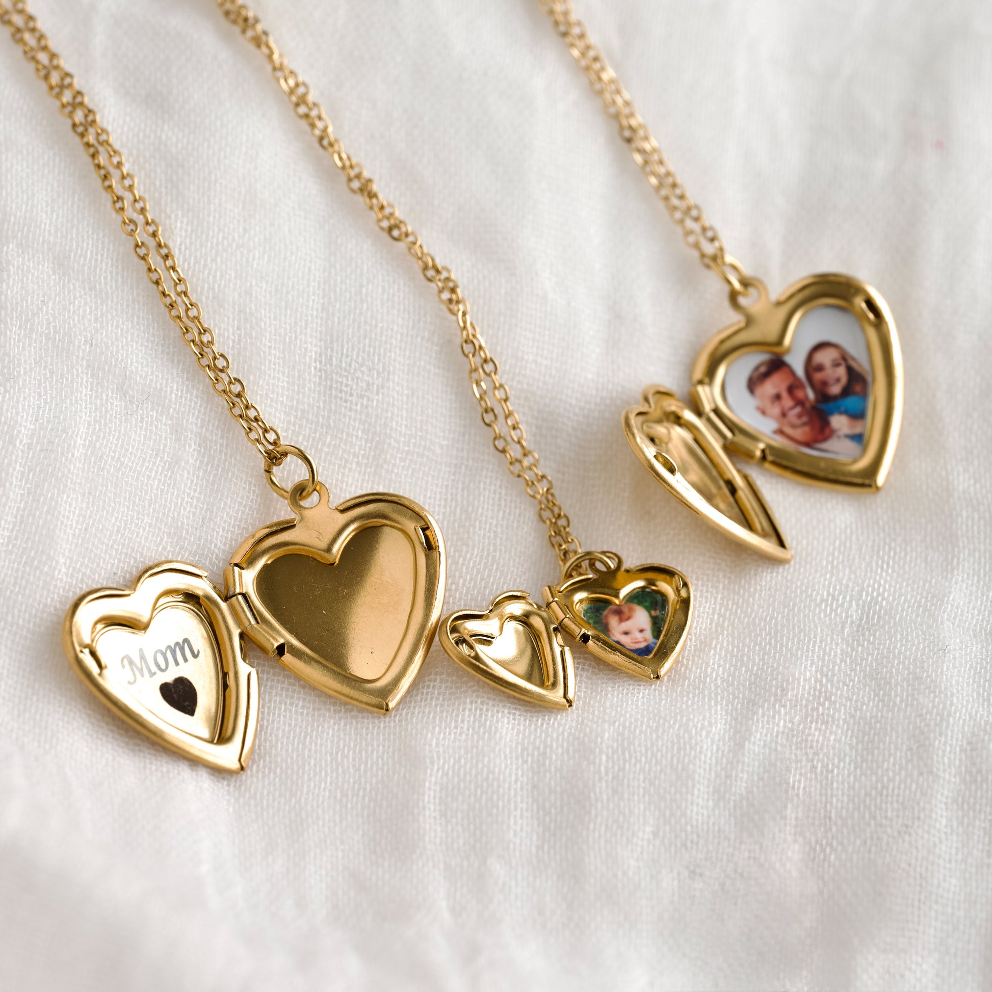 Gold heart-shaped photo locket necklaces, showing the inside engraving 'Mom <3' in one and family photos in the other two,  on a white background