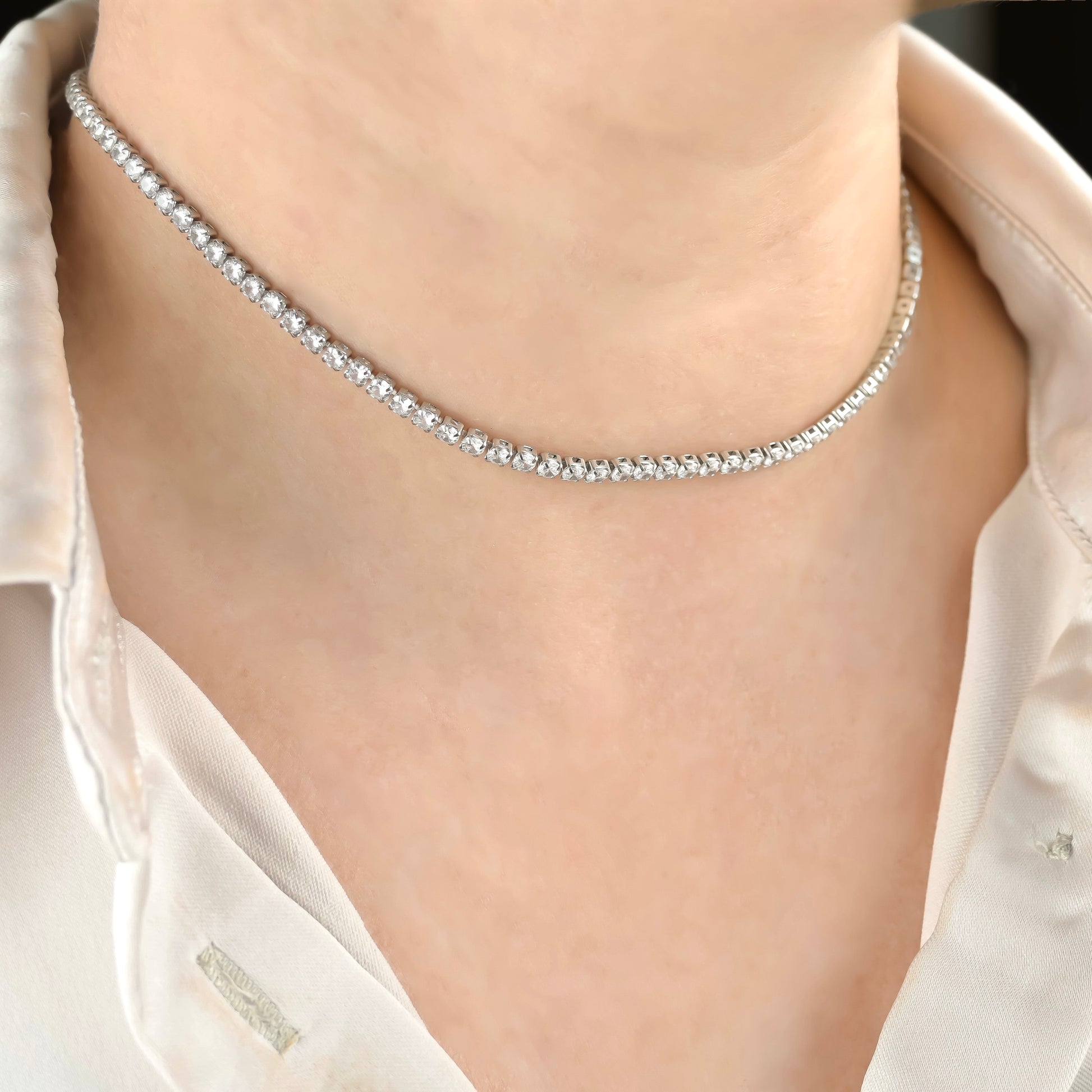 Silver diamond necklace on a person wearing a white shirt