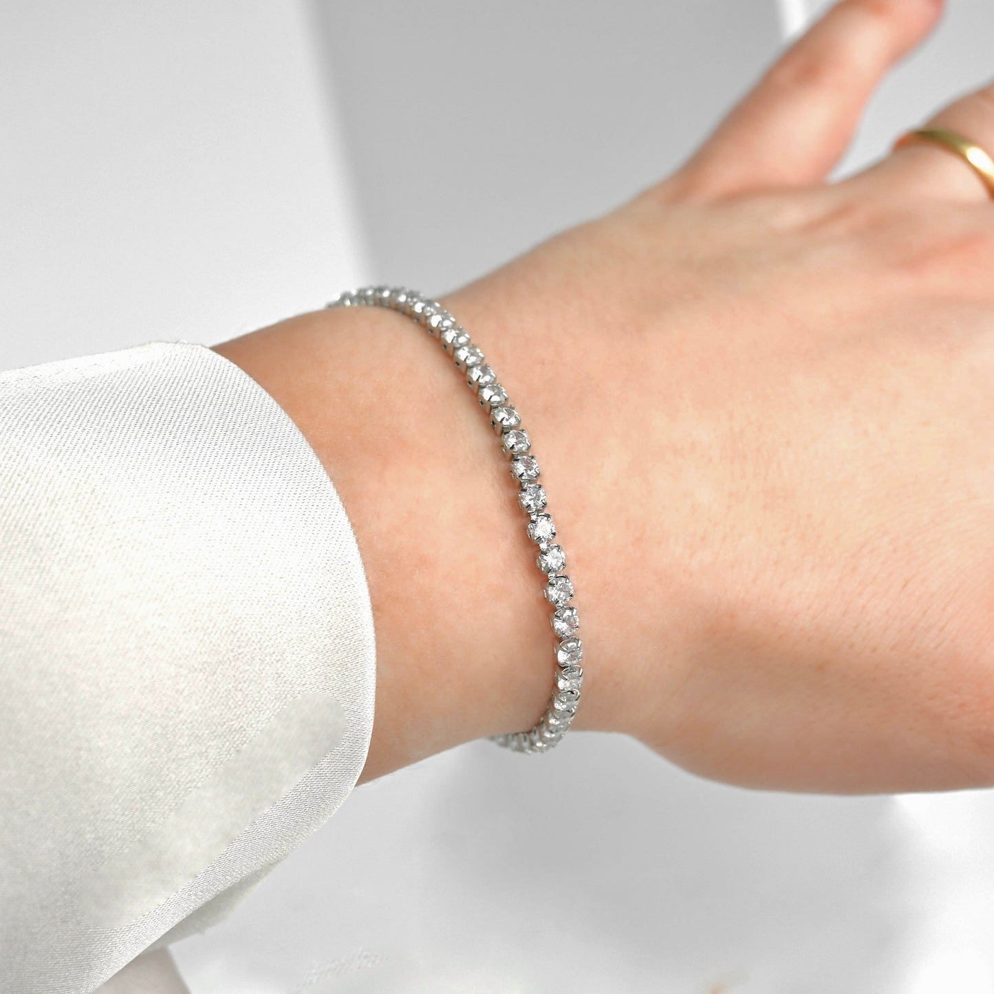 Silver tennis chain bracelet on a wrist with a blurred background