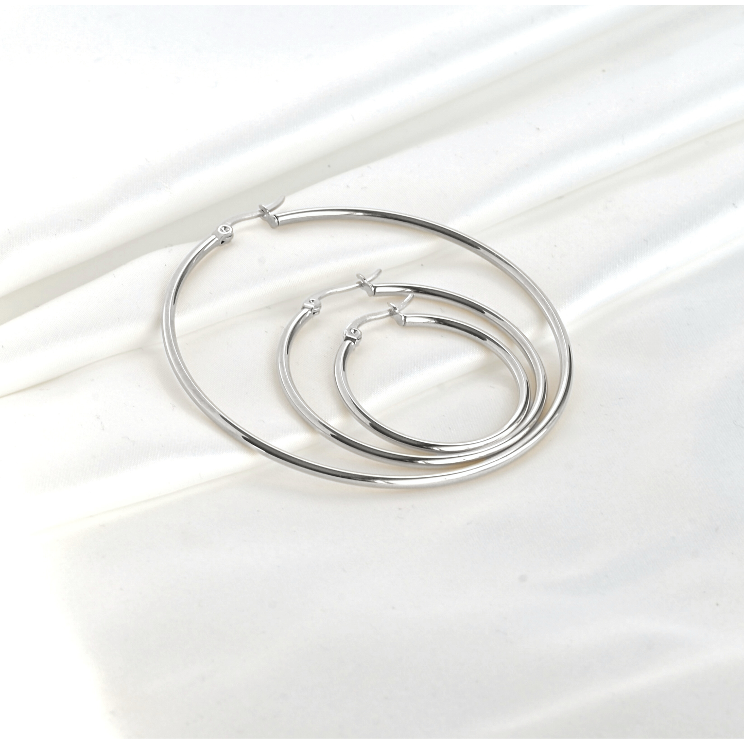 Set of dainty silver hoop earrings on a white background
