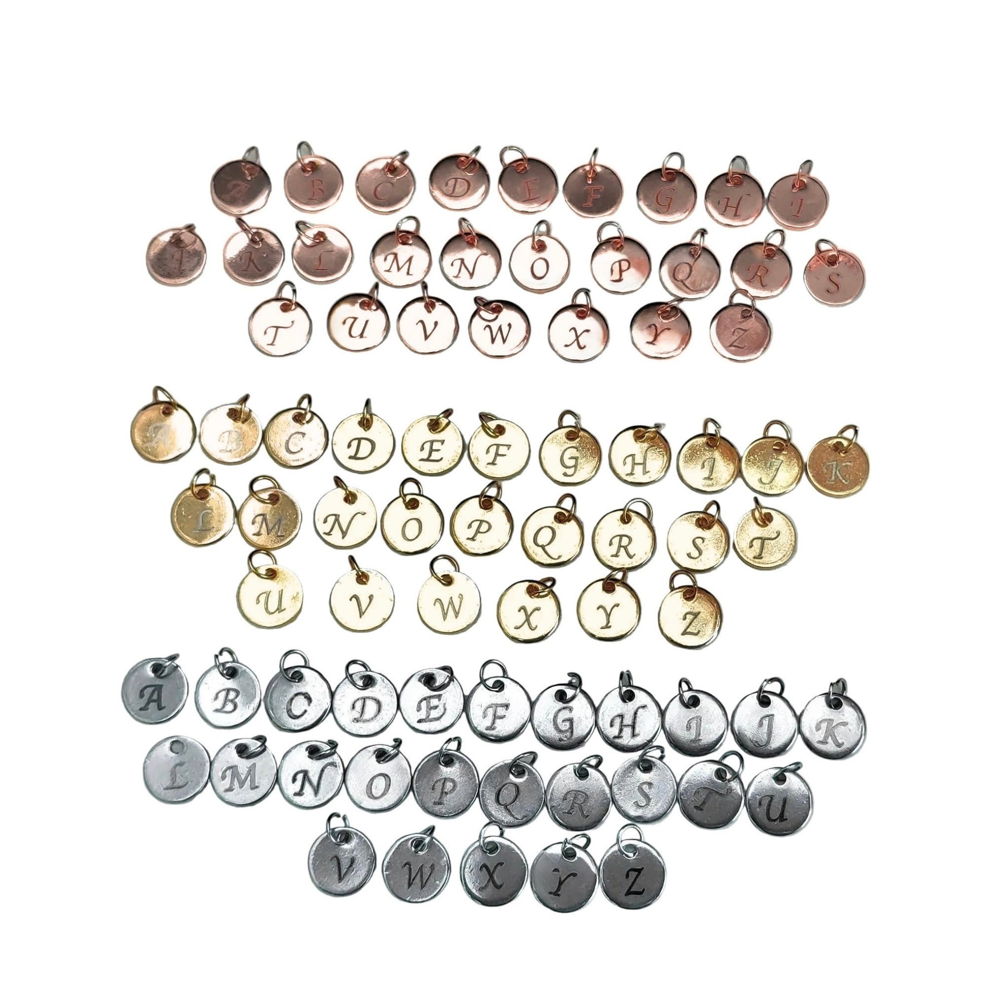 Collection of stainless steel round 8mm letter engraved charms in silver, gold and rose gold on a white background