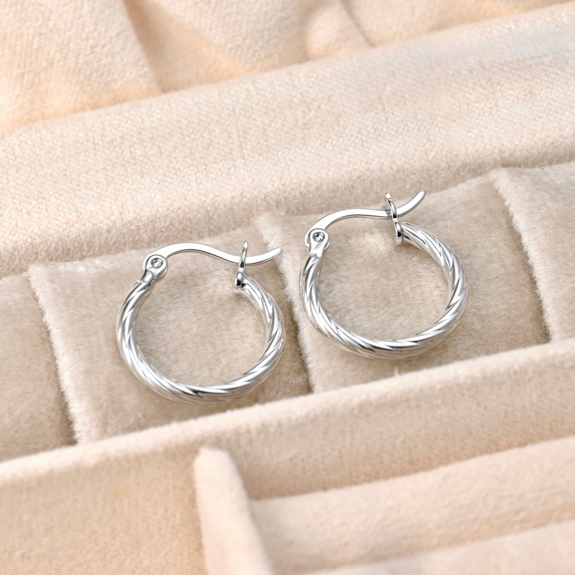 dainty silver hoop earrings on a beige jewelry display