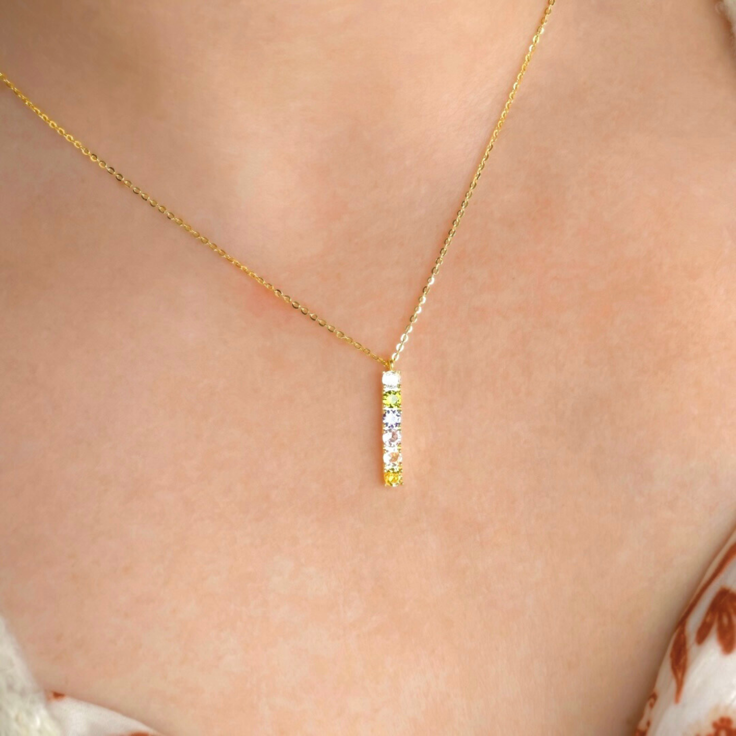 Goldnecklace with a small birthstone bar pendant and a fine cable chain on a person's neck