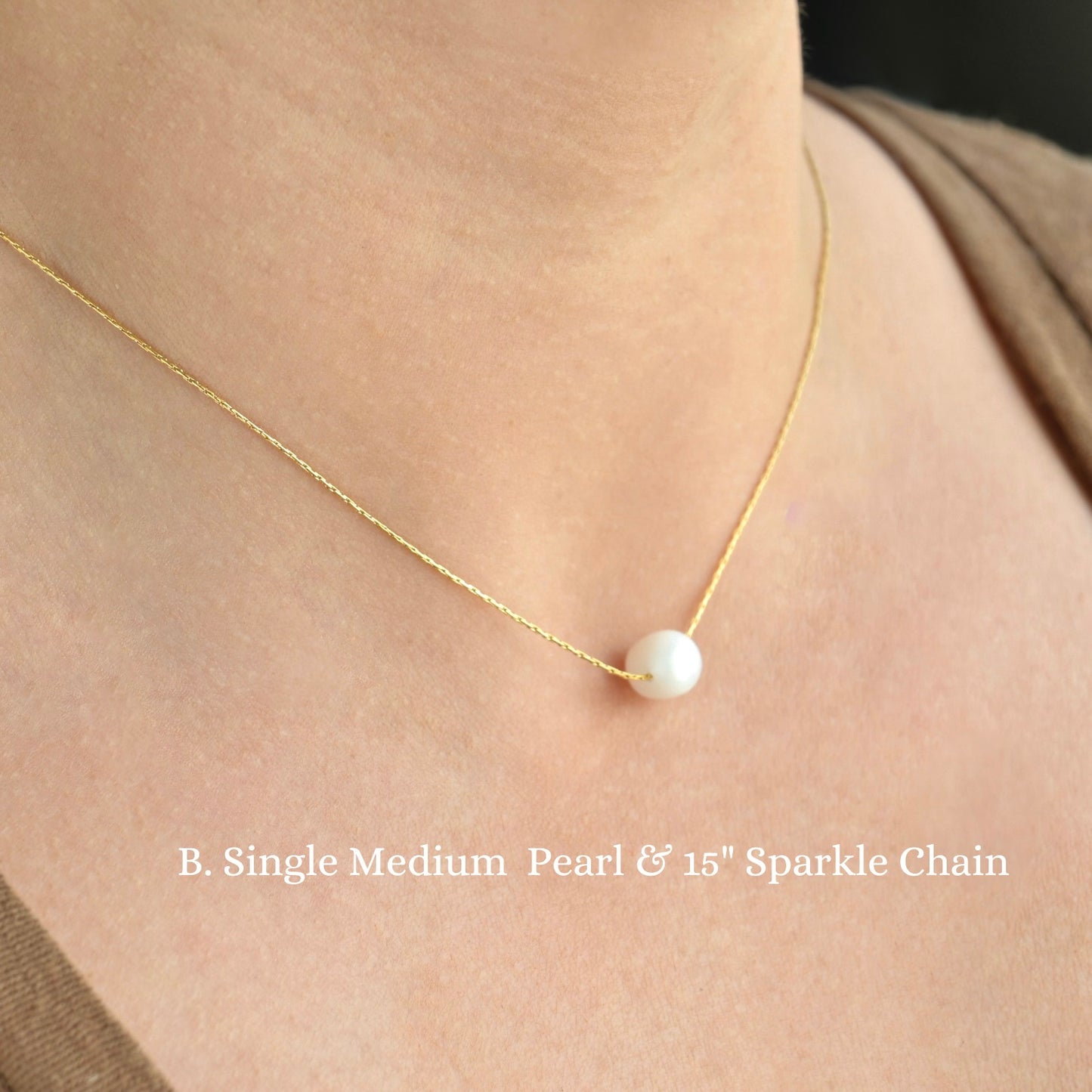 Gold necklace with a single medium pearl and 15-inch sparkle chain on a person wearing a beige top.