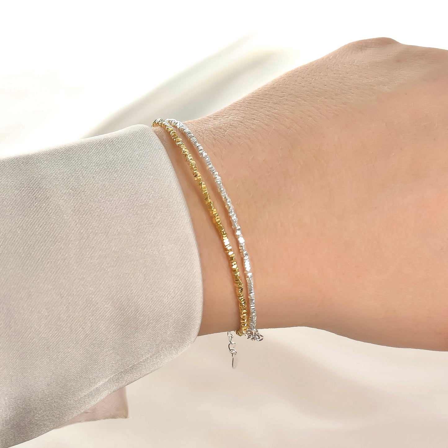 Two beaded bracelets on a wrist with a neutral background
