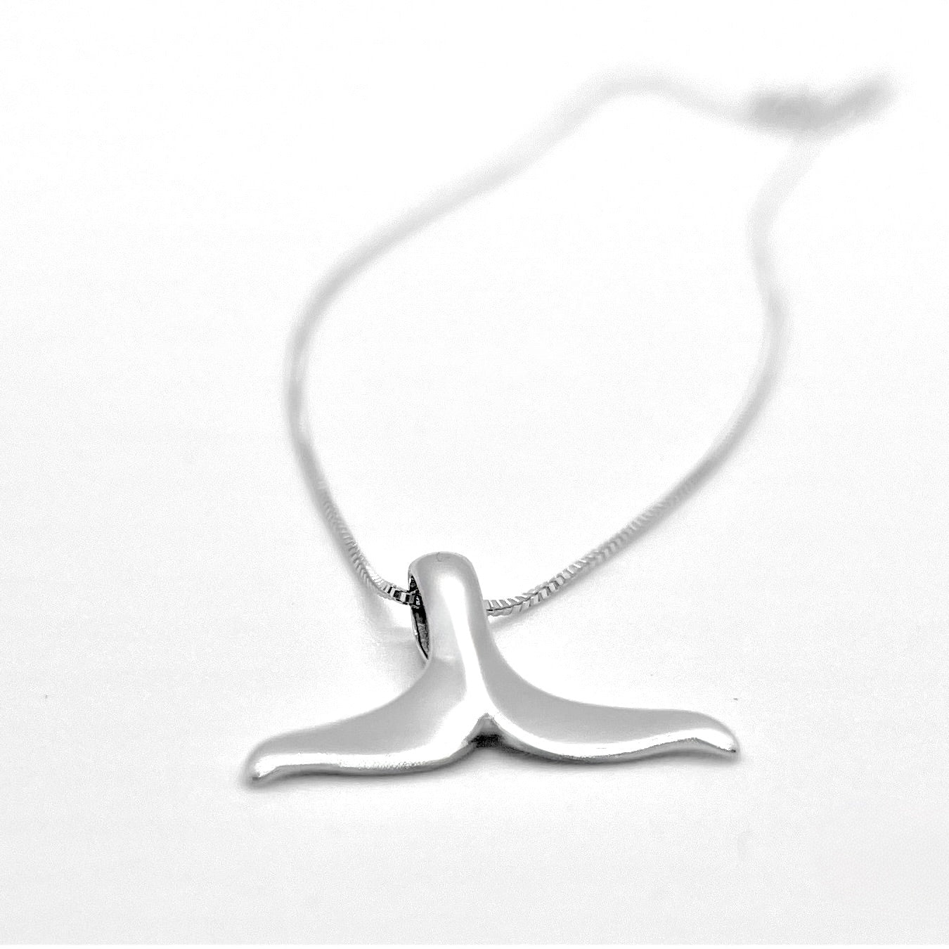 Silver whale tail necklace on a white background