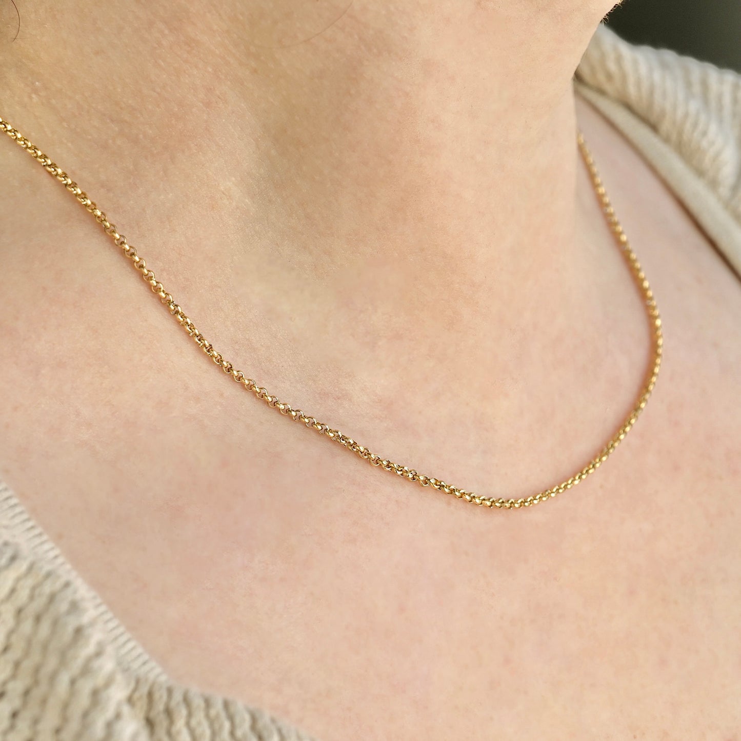Side view of Gold rolo chain necklace on a person's neck 