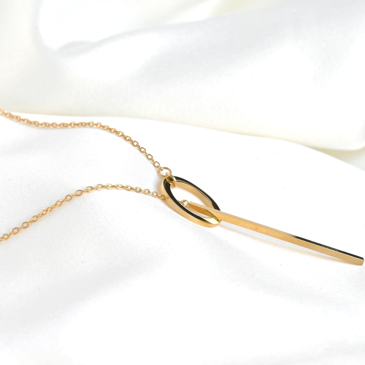 Side close up view of gold necklace with a unique pendant on a white background