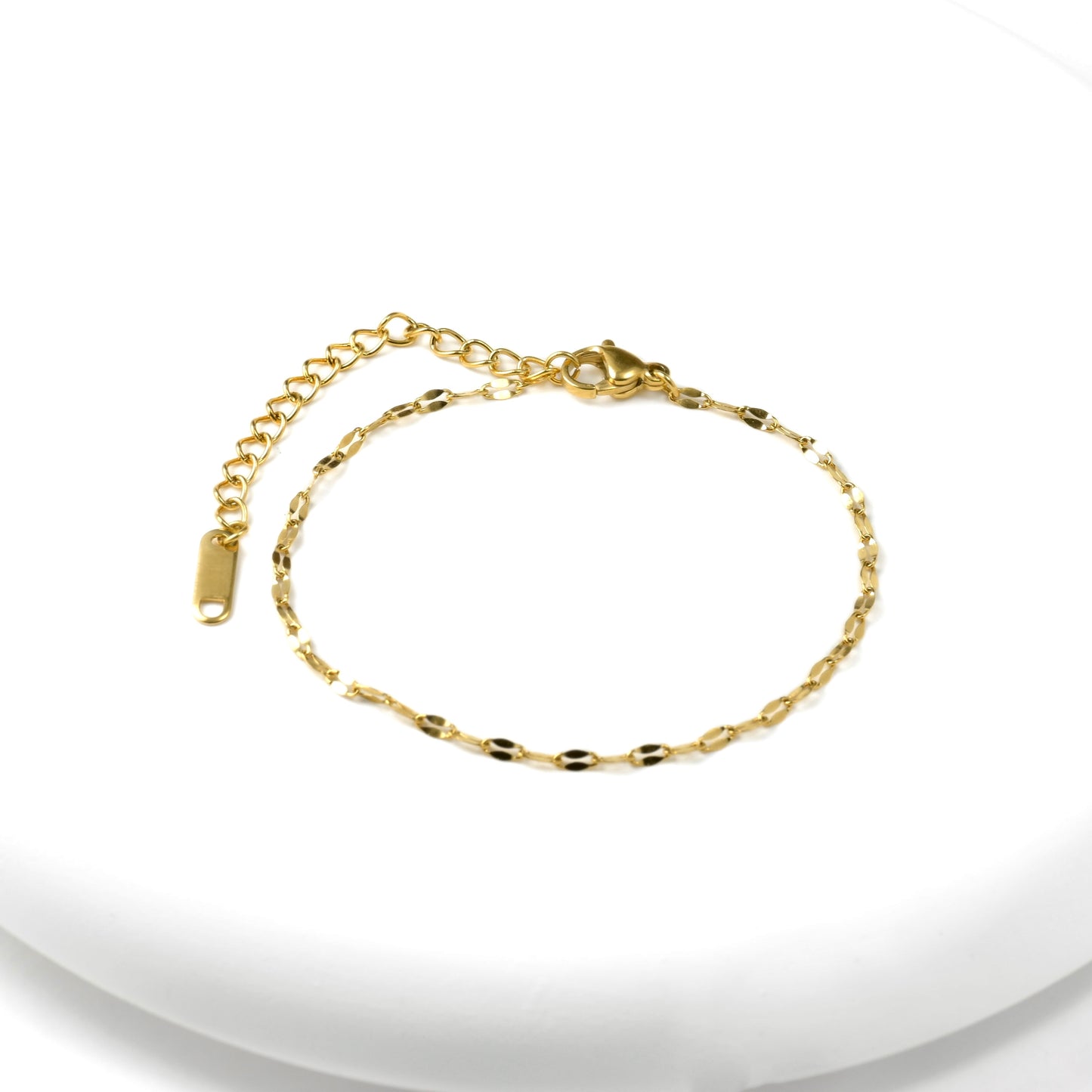 Top view of gold mariner chain bracelet  with a lobster claw clasp, extender and K18 plating hallmark tag on a white background
