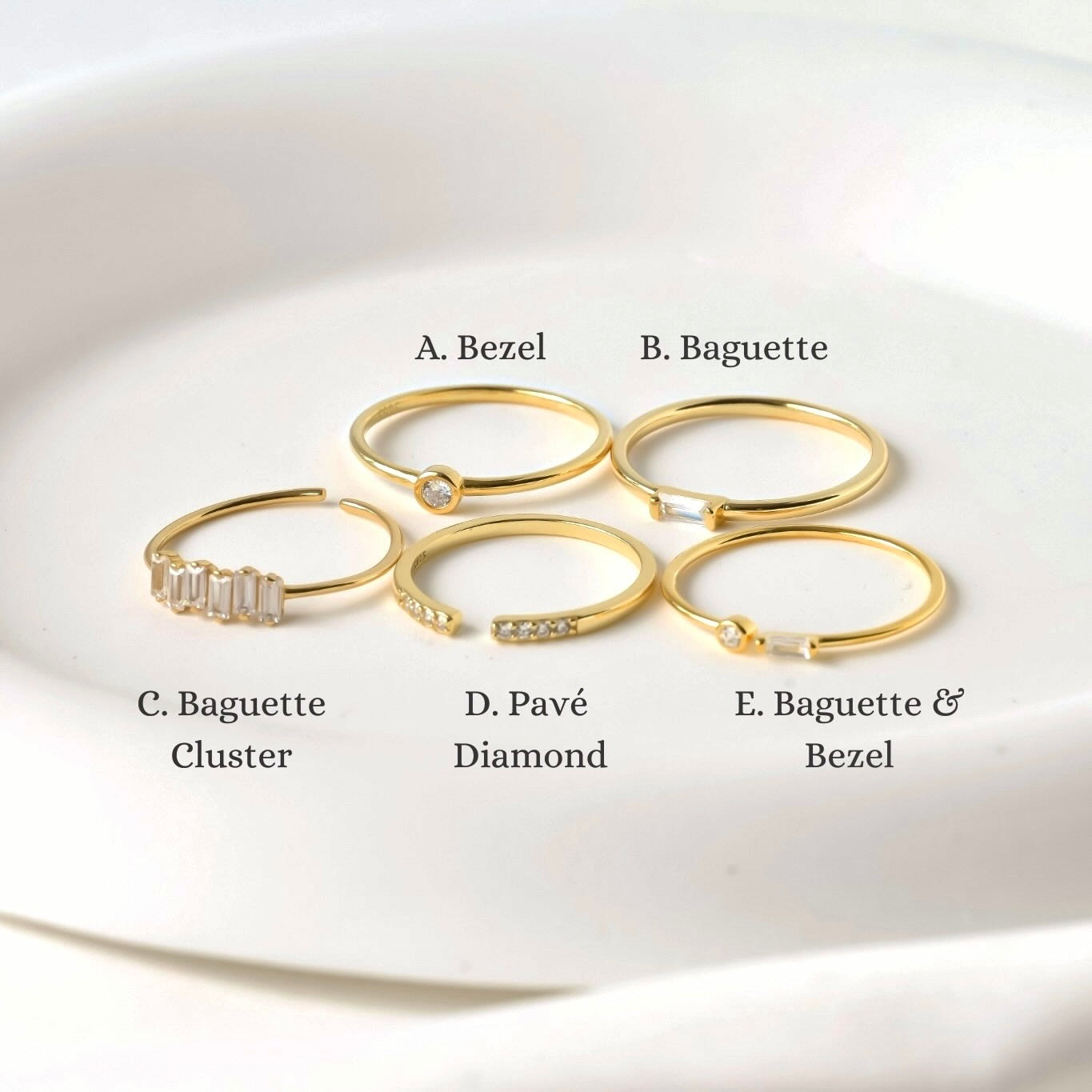Set of slim gold rings with baguette and round stones in  bezel, bar and pave settings on a white background