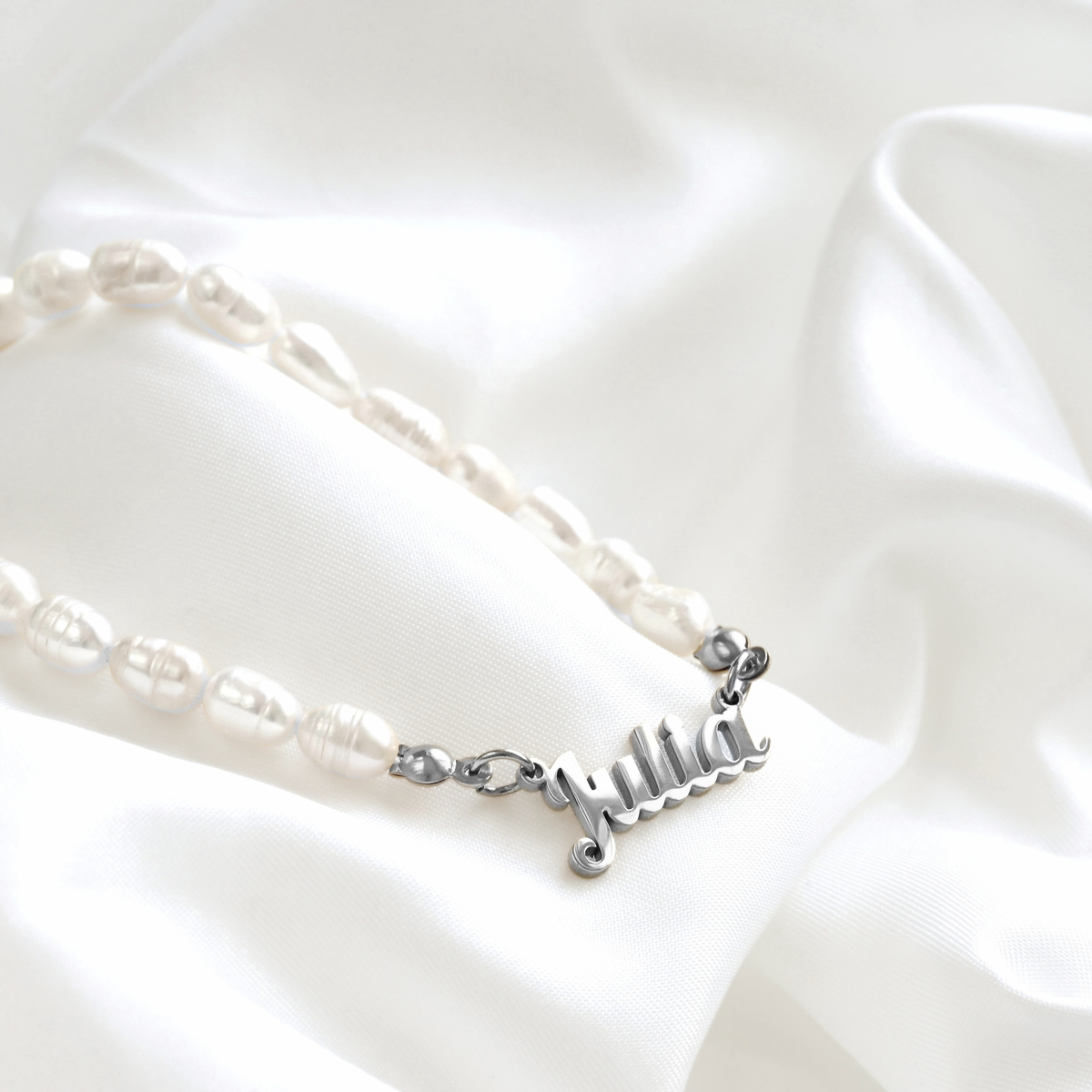 Barque freshwater pearl necklace with the name "Julia" in silver stainless steel draped on white satin.