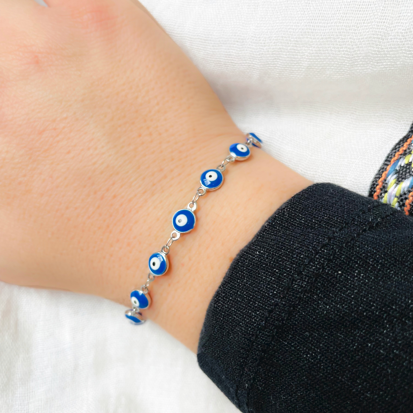 Silver evil eye bead bracelet on a wrist against a white background