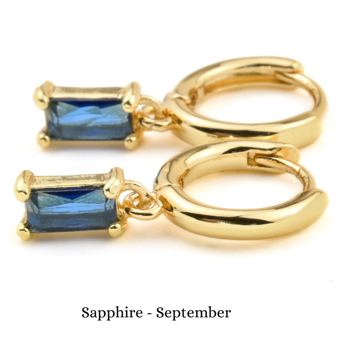 Gold hoop earrings with sapphire gemstones on a white background