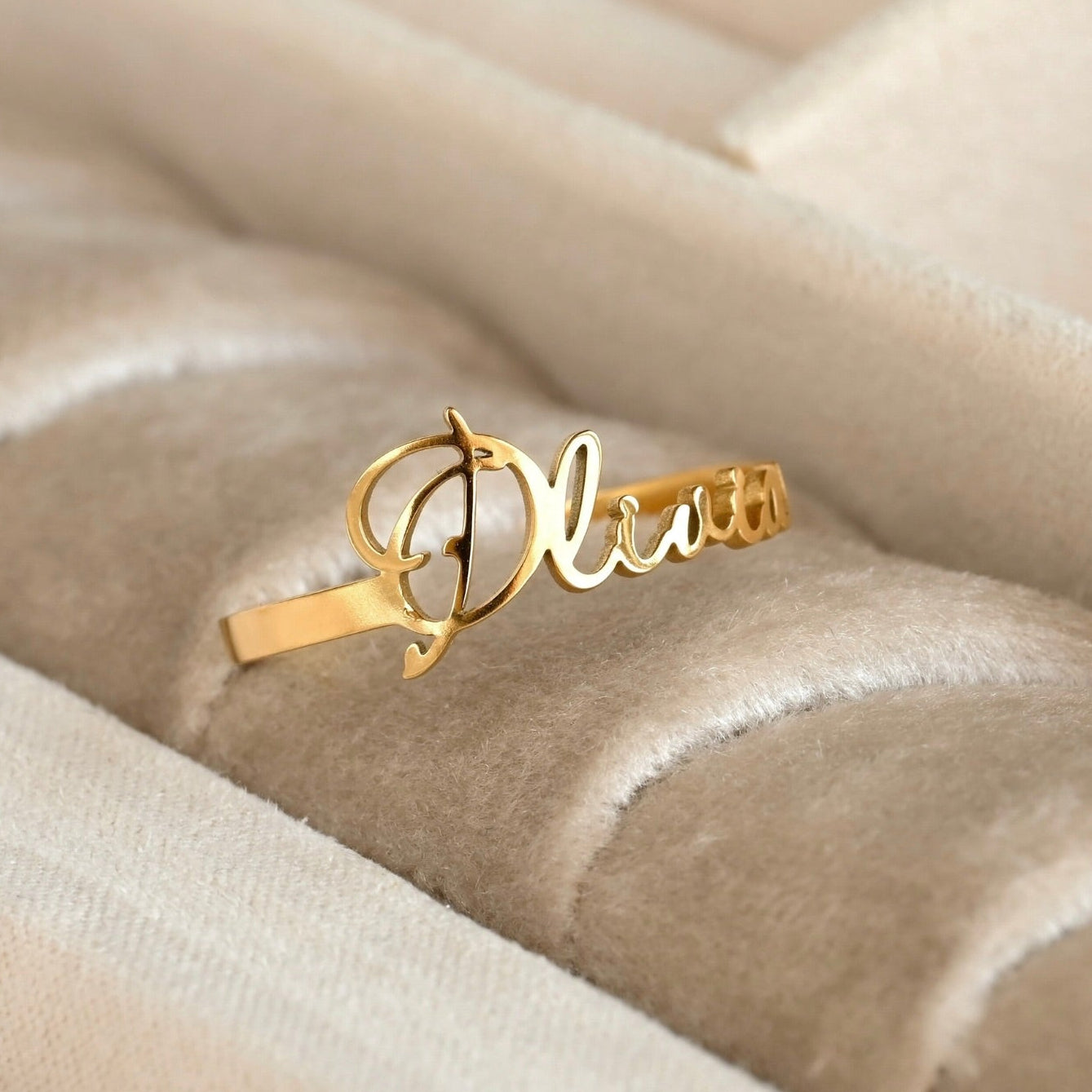 Personalized Gold name ring with 'Olivia' script on a beige textured surface
