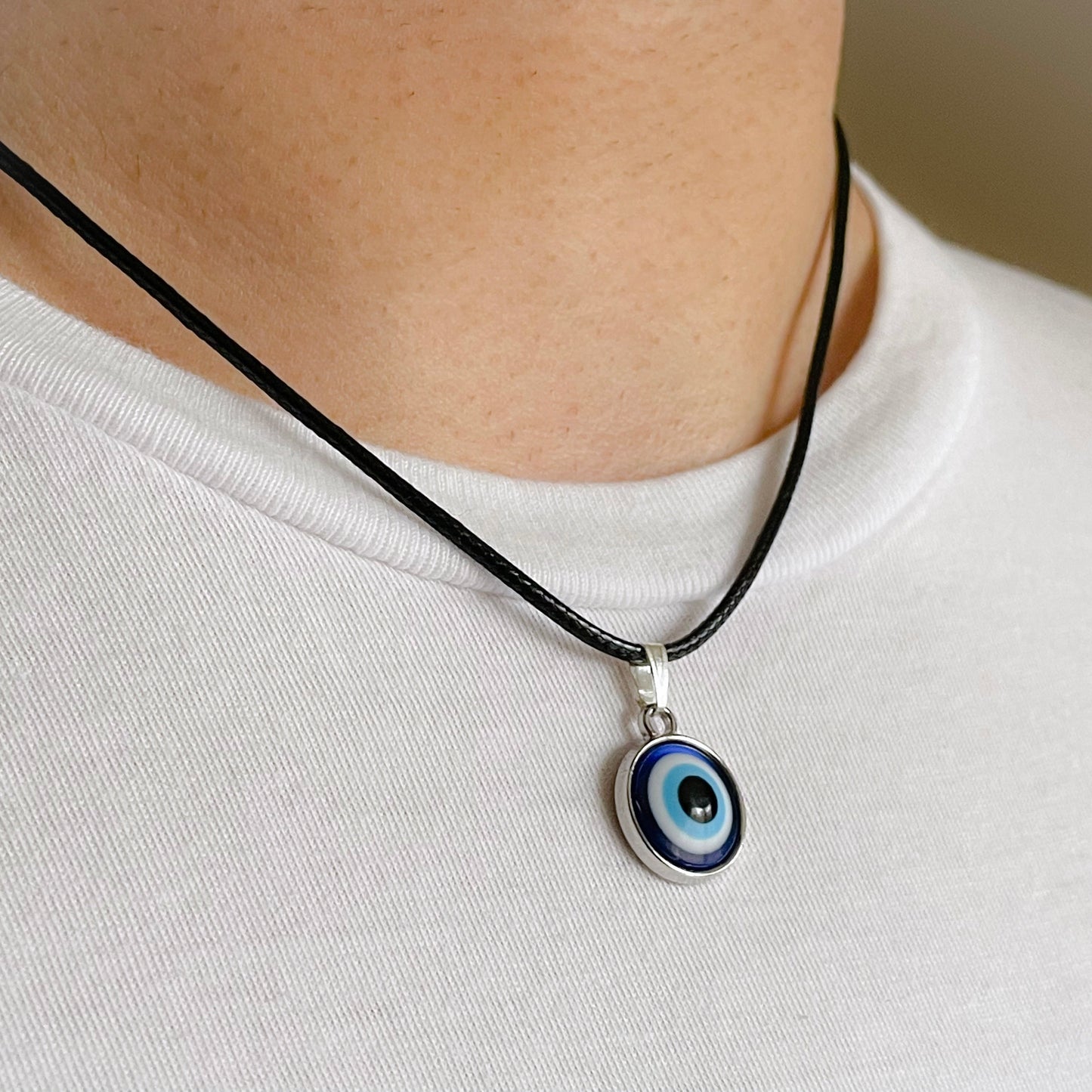 Necklace with an eye-shaped pendant worn by a man on a plain background