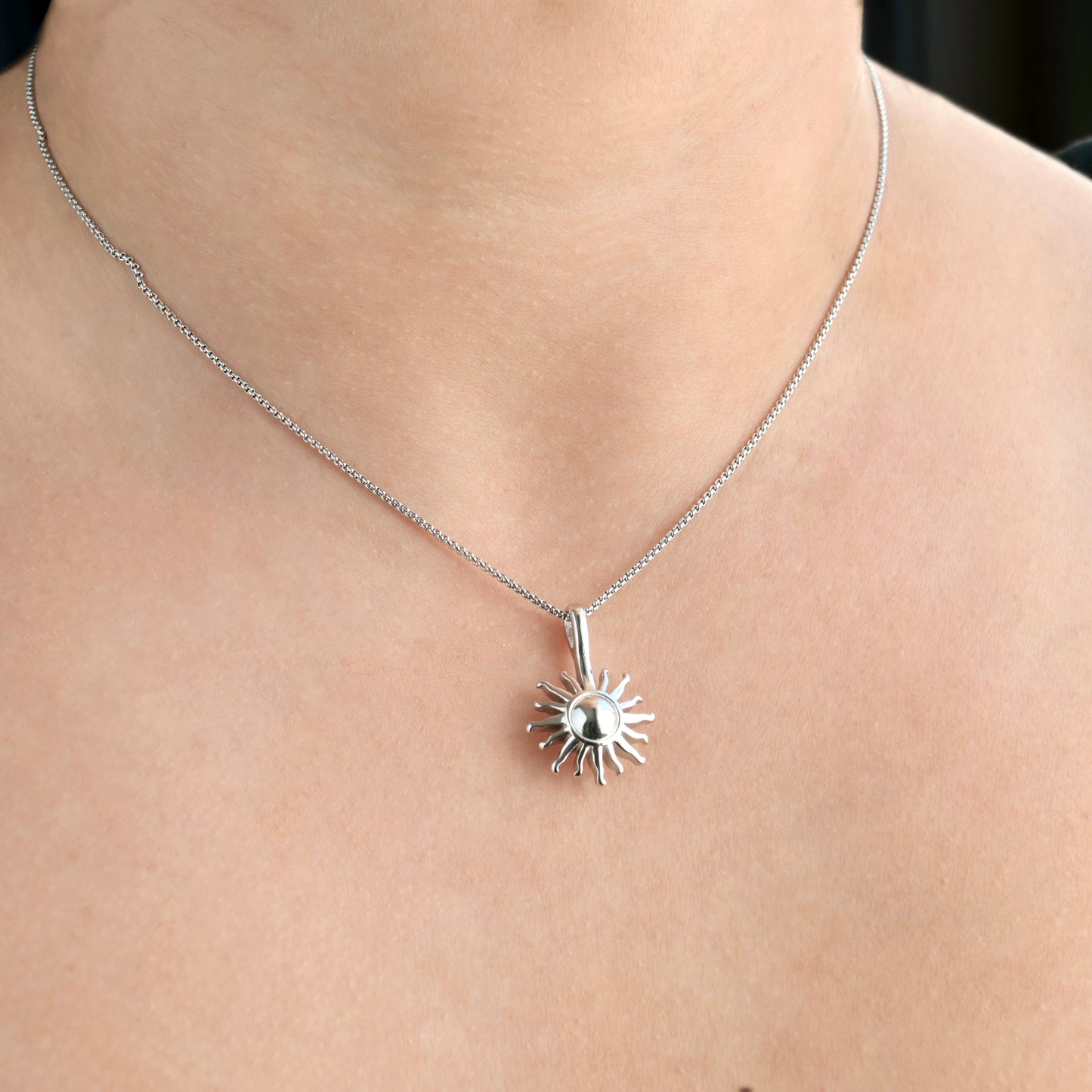 Silver sun necklace on a person's neck