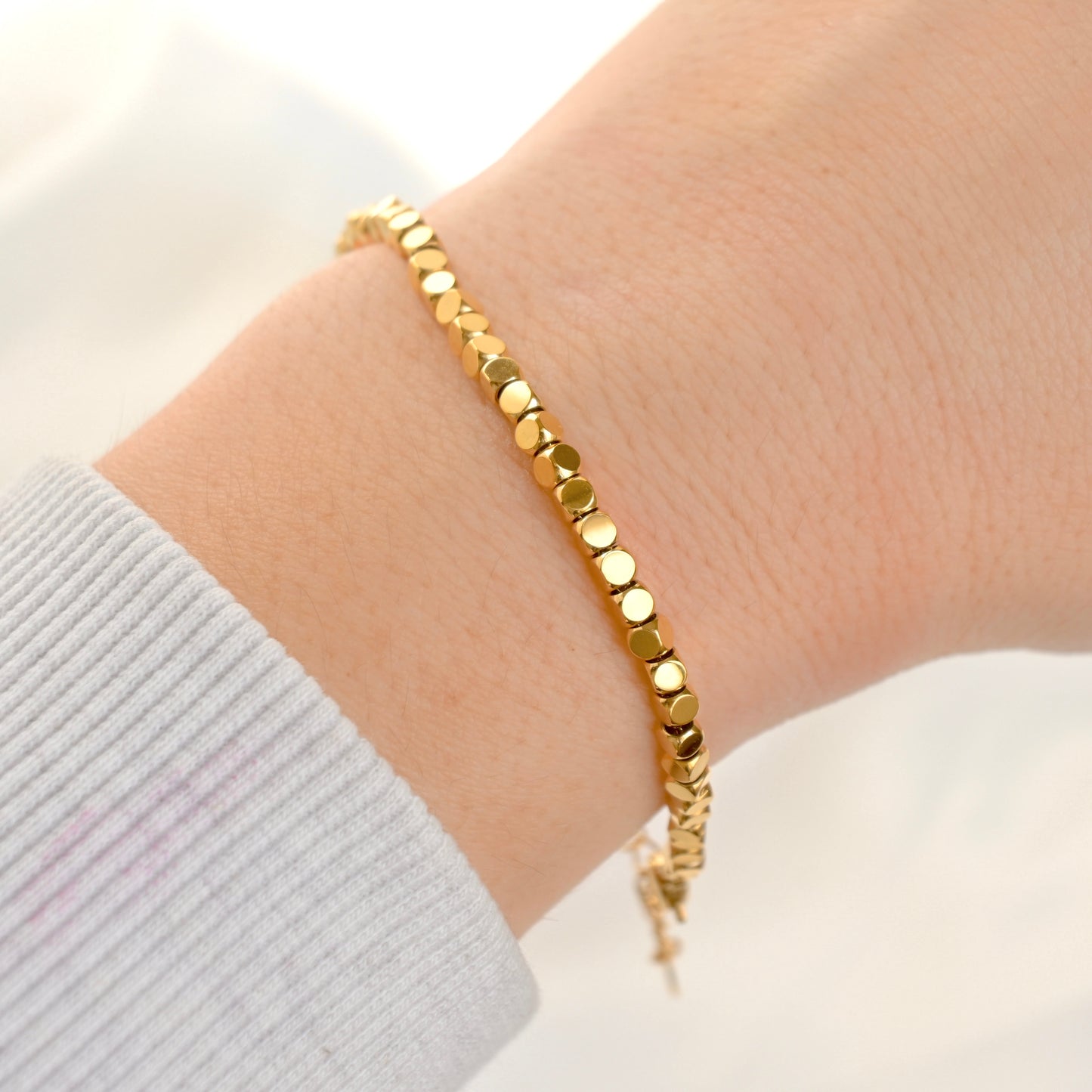 Gold Cube bead bracelet on a wrist with a light background