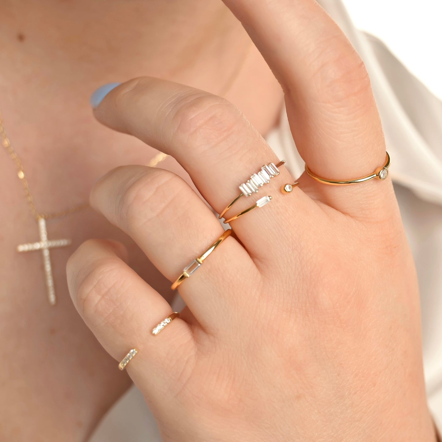 Hand wearing multiple gold rings with clear stones a blurred background
