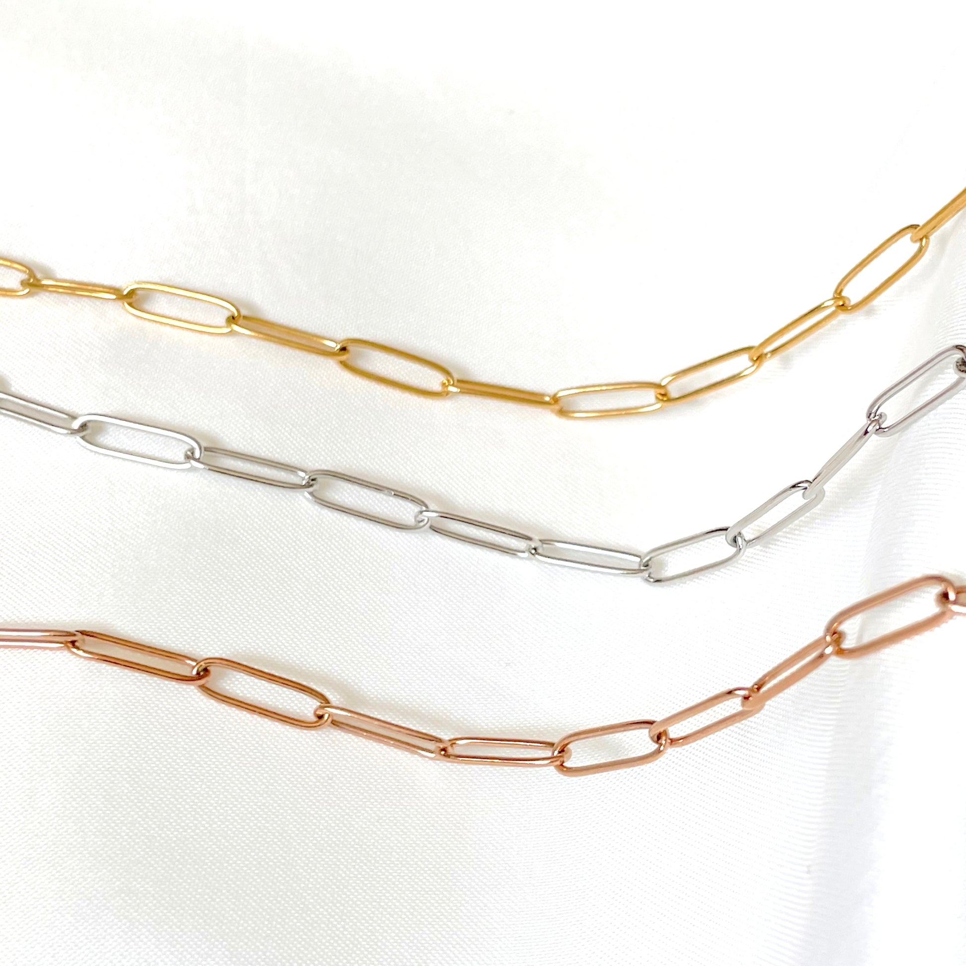 Three gold, silver, and rose gold link chain necklaces on a white background