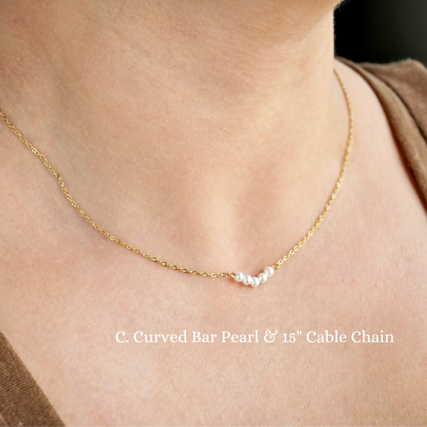 Gold necklace with curved bar pearl and cable chain on a person's neck