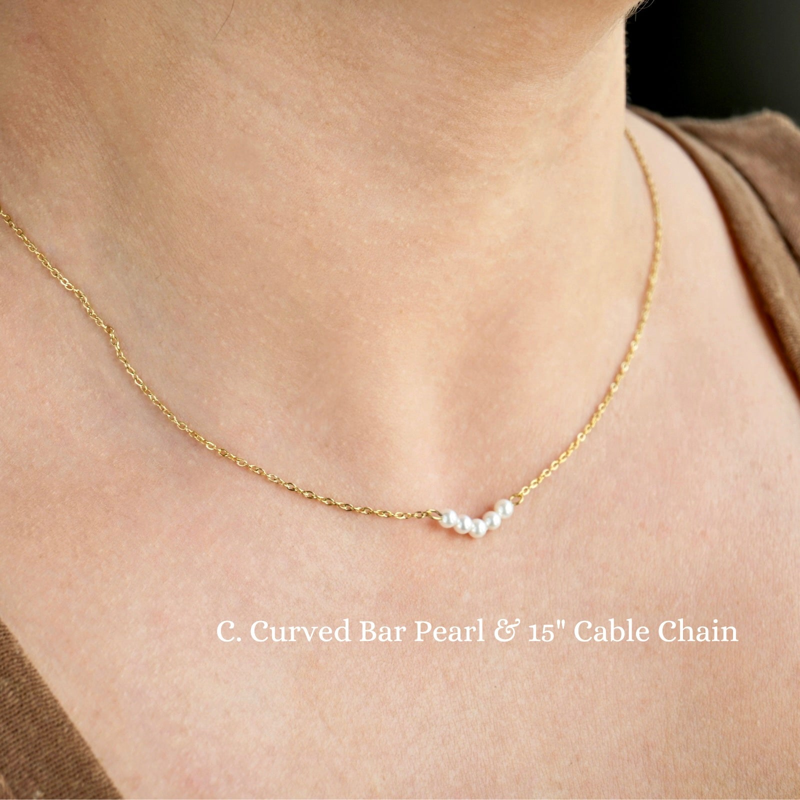 Gold necklace with curved bar pearl and cable chain on a person's neck