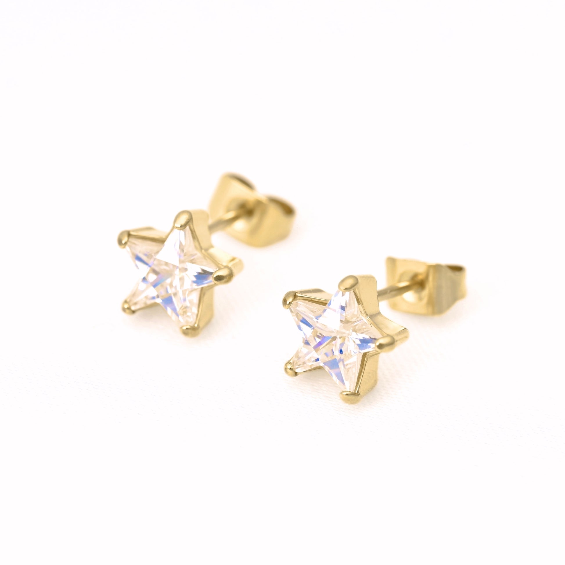 A pair of gold star-shaped stud earrings with clear faceted crystals, shown on a plain white background.