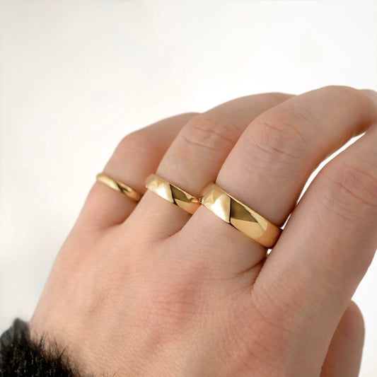 Hand wearing Three polished gold bands of different widths 