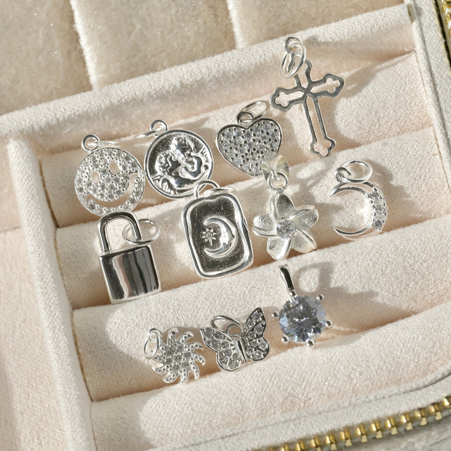 Collection of silver charms in a jewelry box under direct sunlight